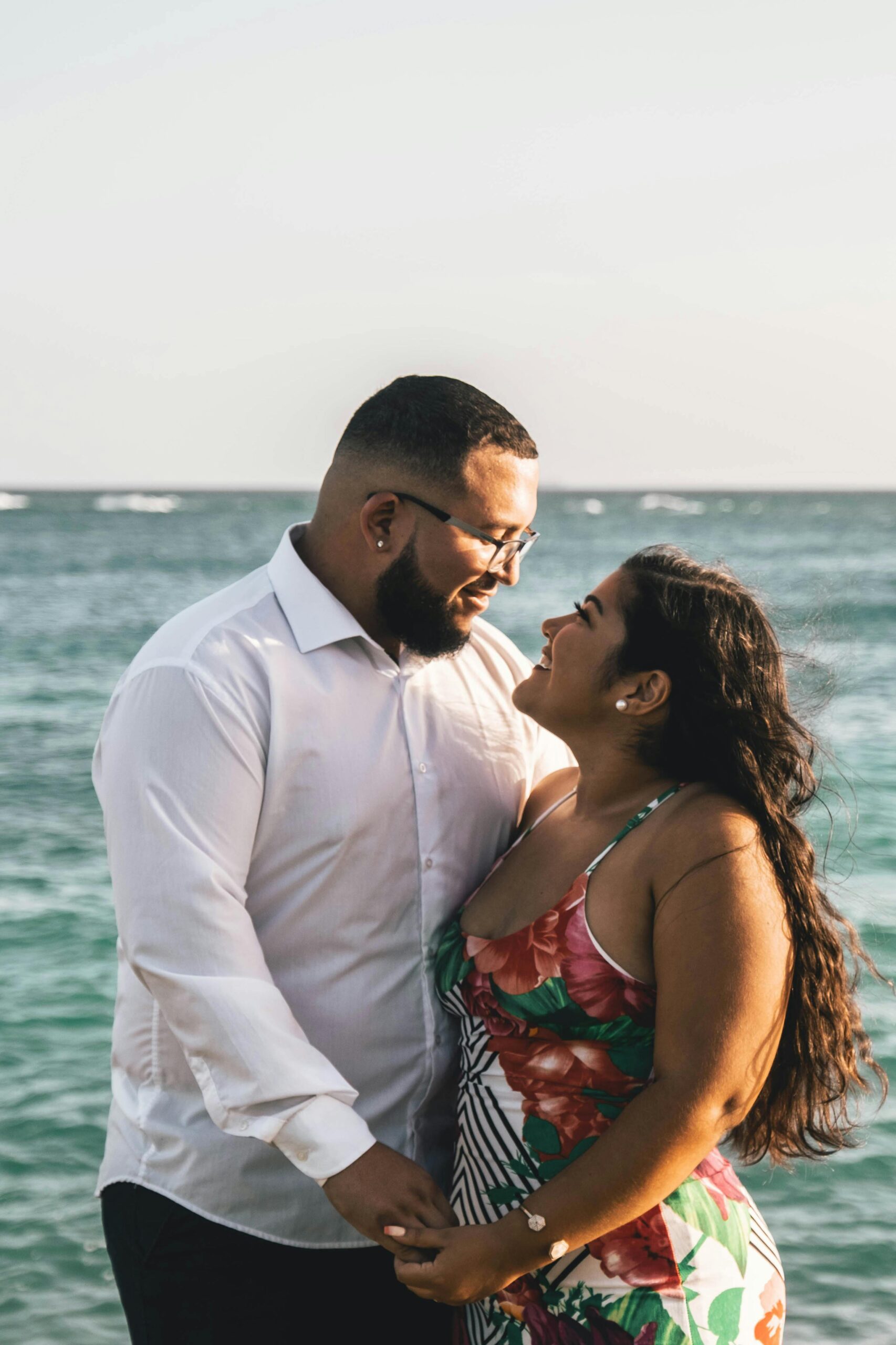 Man n Women looking at each other closely while standing on a beach.