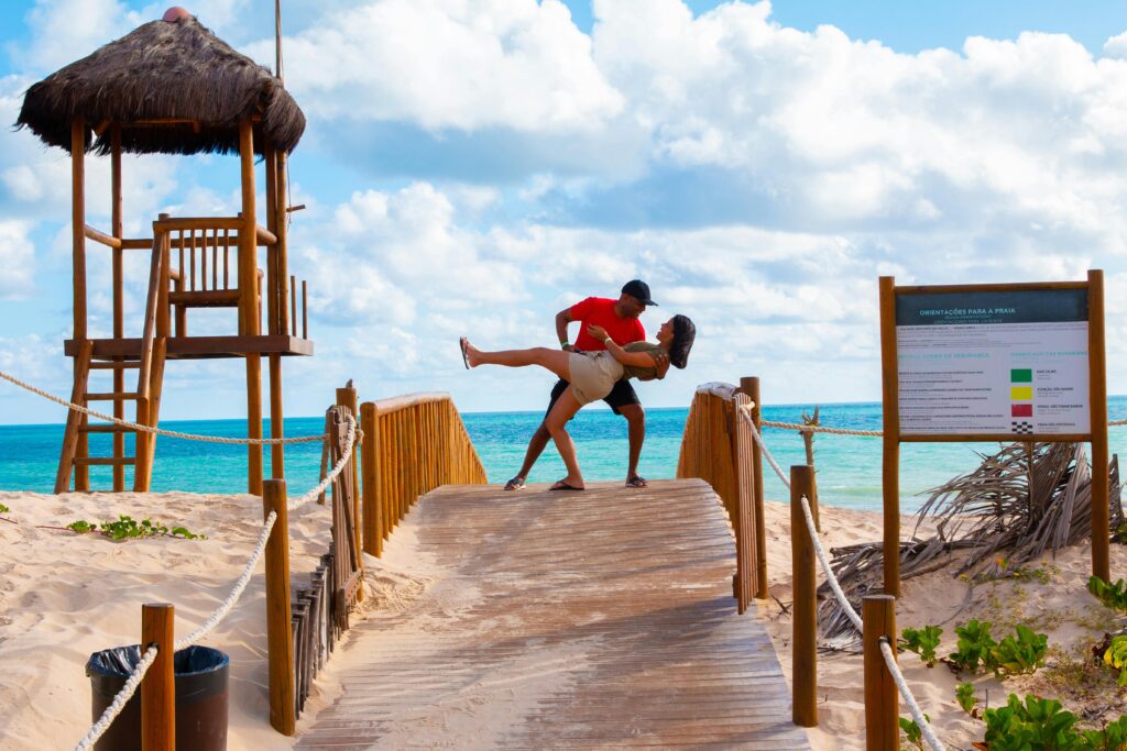 couple on beach bridge playing.  Brown bridge, blue water, sand