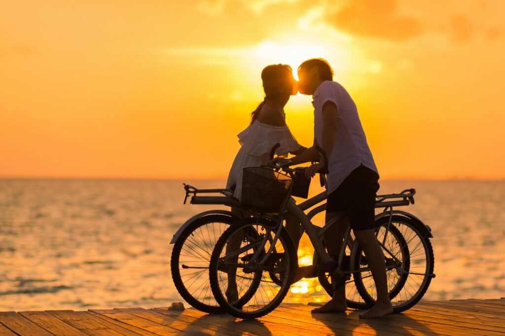 man and woman on bikes on beach kissing romance and adventure honeymoon