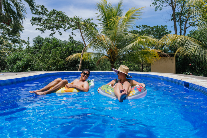 Happy couplw floating on tubs in the pool while holding hands